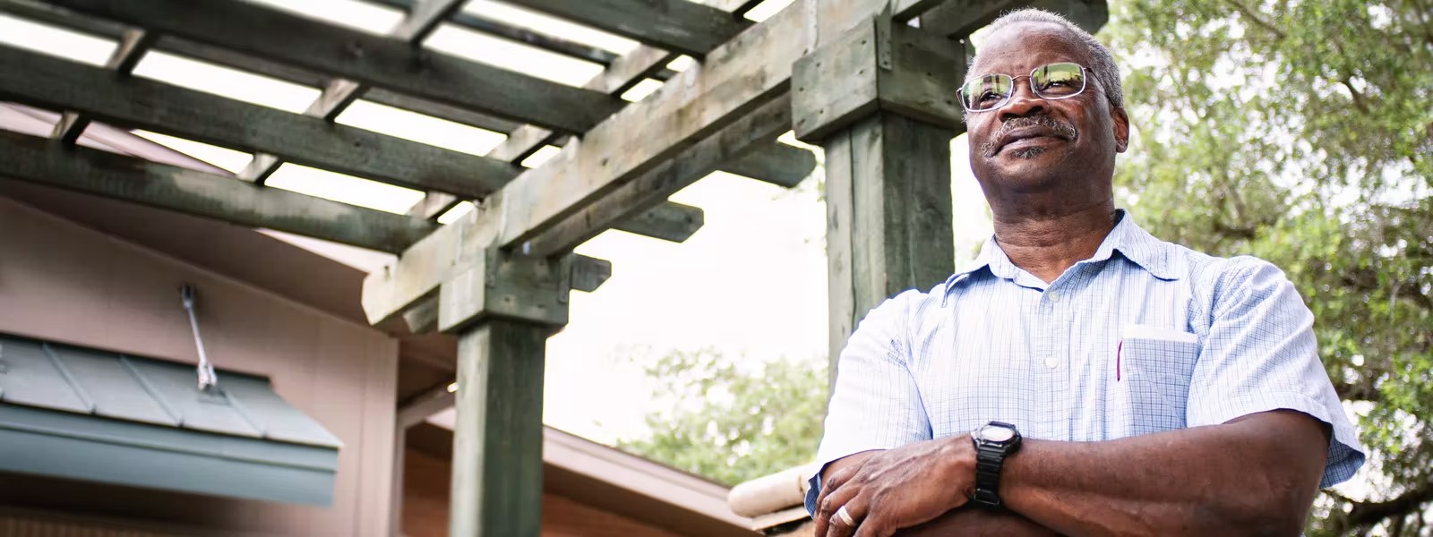 A man wearing glasses, smiling and with his arms crossed